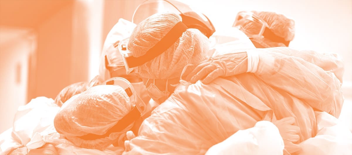 A group of masked surgeons huddling and hugging in their medical uniform
